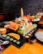 Sushi-Turm auf Schieferplatte vor dunkler Ziegelwand